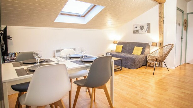 Un coin repas avec une table dressée pour deux personnes, un canapé et un fauteuil.
