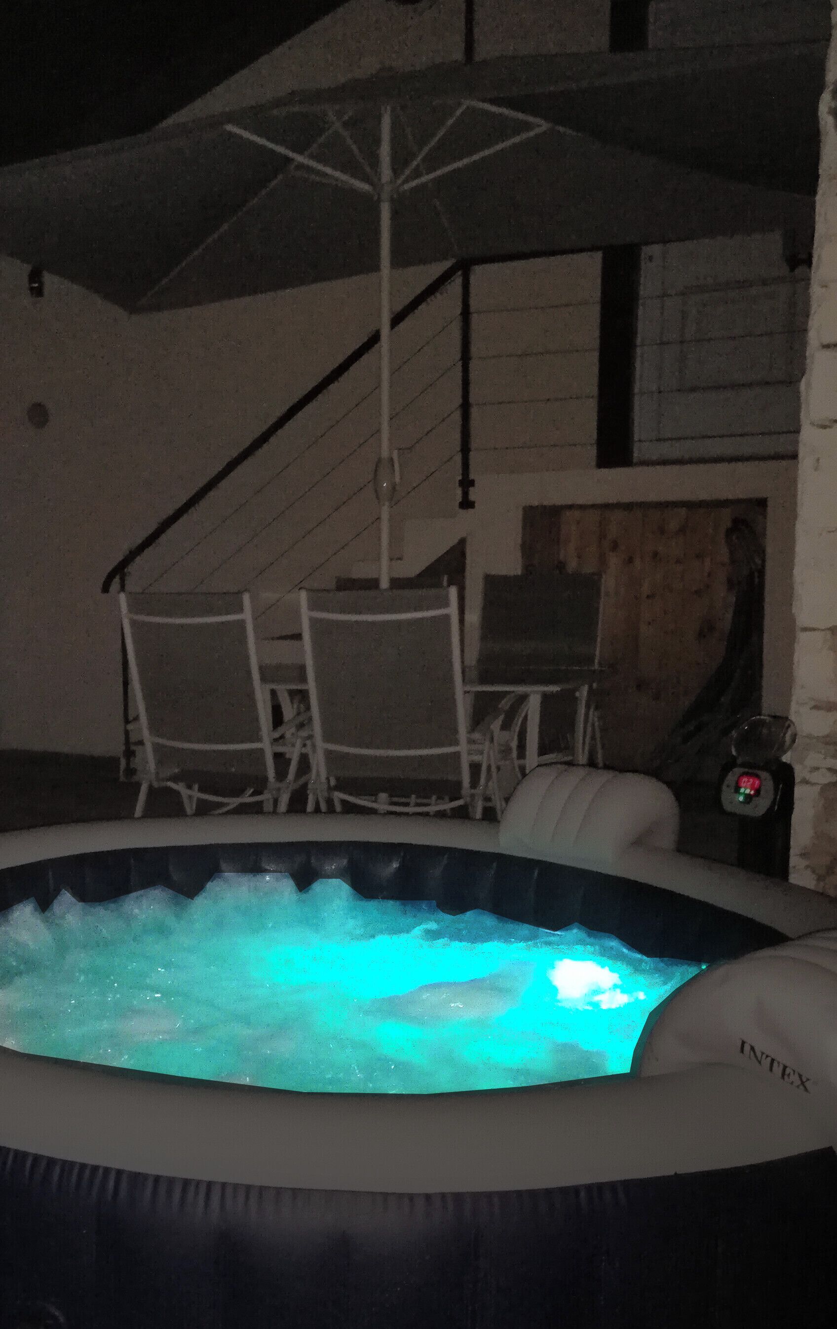 An indoor hot tub with a wooden ceiling and a staircase in the background.