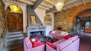 Una sala acogedora con chimenea, sofás estampados de cuadros y una pared de piedra.