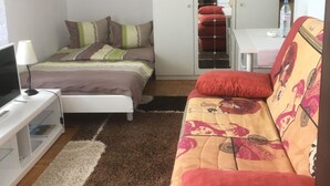 Ett sovrum med en säng, en soffa, en tv, en garderob och ett skrivbord.