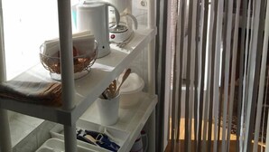 Ett kök med vita hyllor, en mikrovågsugn, en kaffebryggare och en vattenkokare.