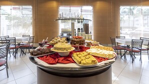 A buffet with various desserts and beverages, arranged on a central table with chairs around it. - Hotel Plaza Norte (Joinville)