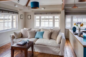A cozy living room with a beige sofa, a wooden coffee table, and a blue pendant light. - Dream Stays Bath - Queen Street (Bath)