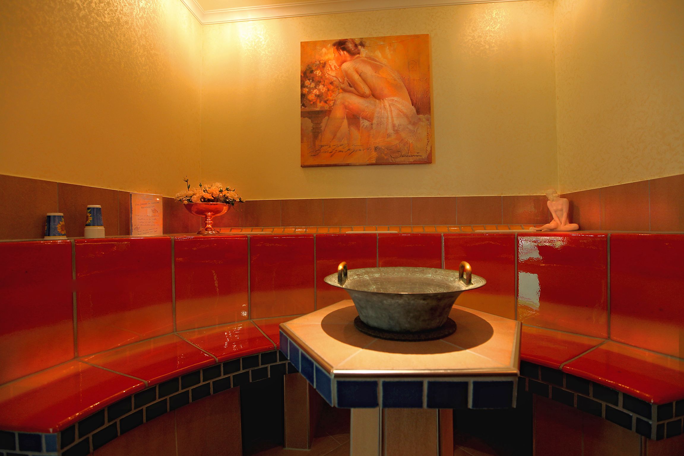 Un área de spa con una bañera grande, asientos rojos y un cuadro en la pared.