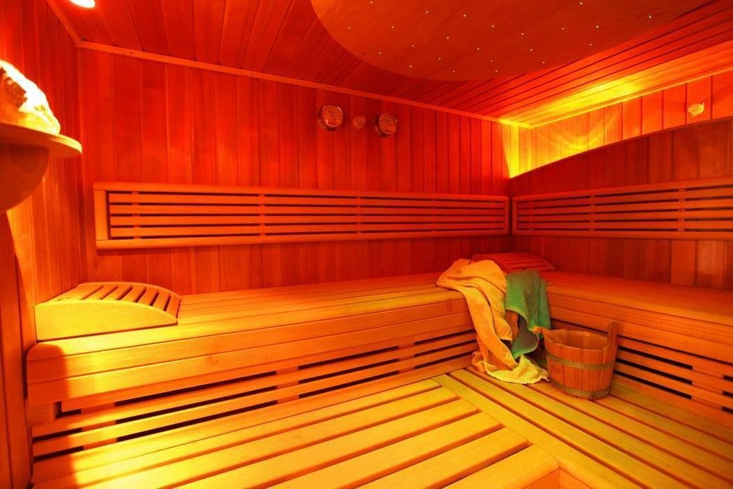 Una sauna con bancos de madera y un banco con una toalla y un cubo.