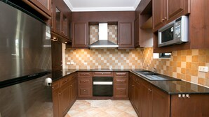 A kitchen with wooden cabinets, a stainless steel refrigerator, a microwave, and a tiled backsplash.