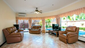 A living room with two leather sofas, a TV, and a ceiling fan.