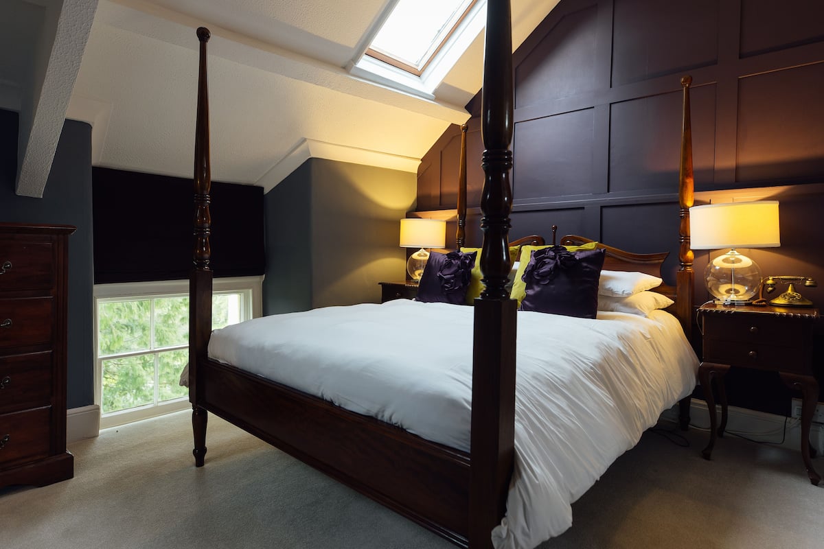 Un lit à baldaquin, une table de chevet avec une lampe et une commode.
