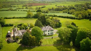 A large, green, leafy estate with a main house, several outbuildings, and expansive fields. - Elm Grove Country House (Tenby)
