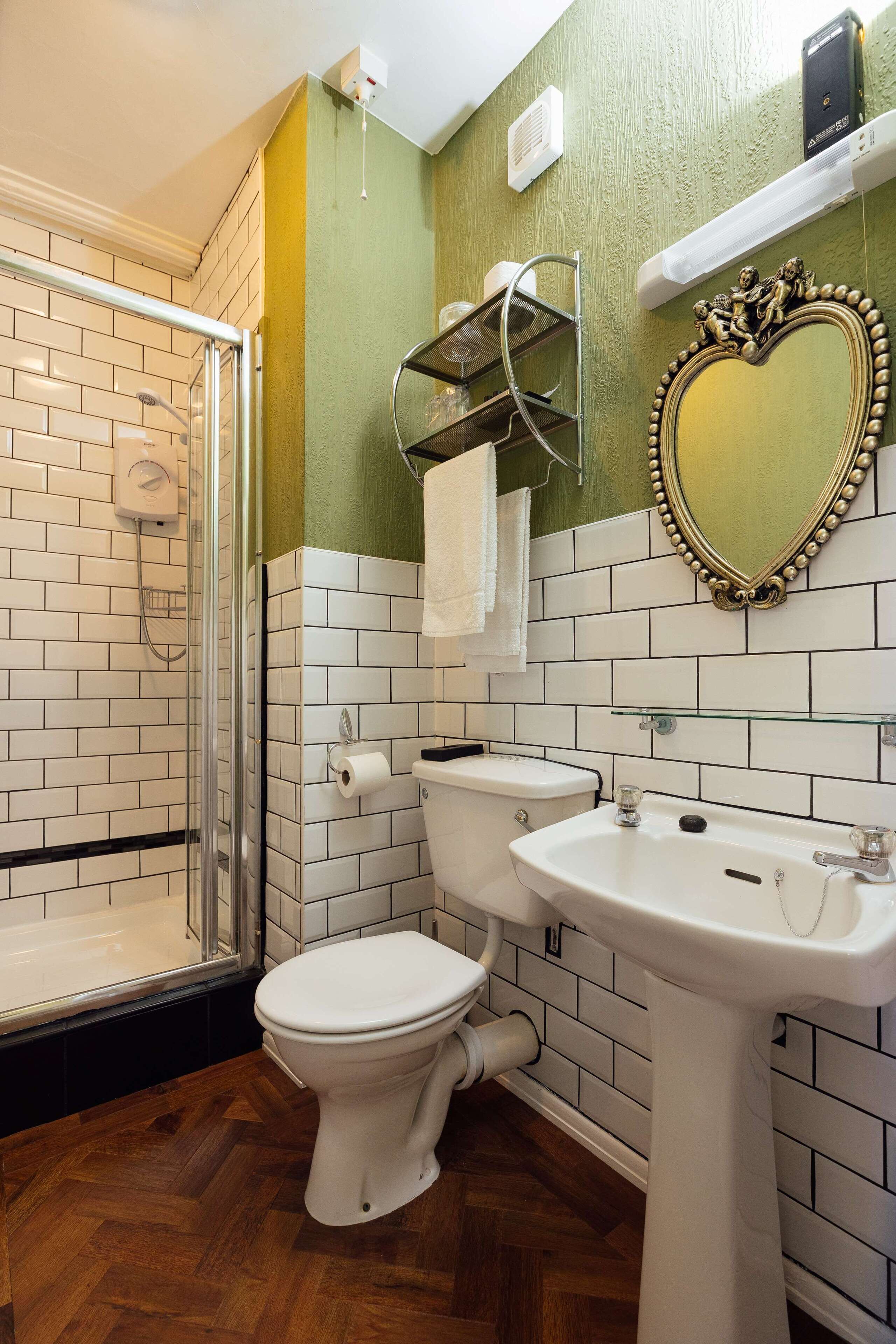 Un baño con inodoro blanco, lavamanos y ducha.
