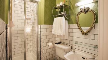 Une salle de bain avec une douche à parois de verre, des toilettes, un lavabo et un meuble-lavabo avec un miroir.