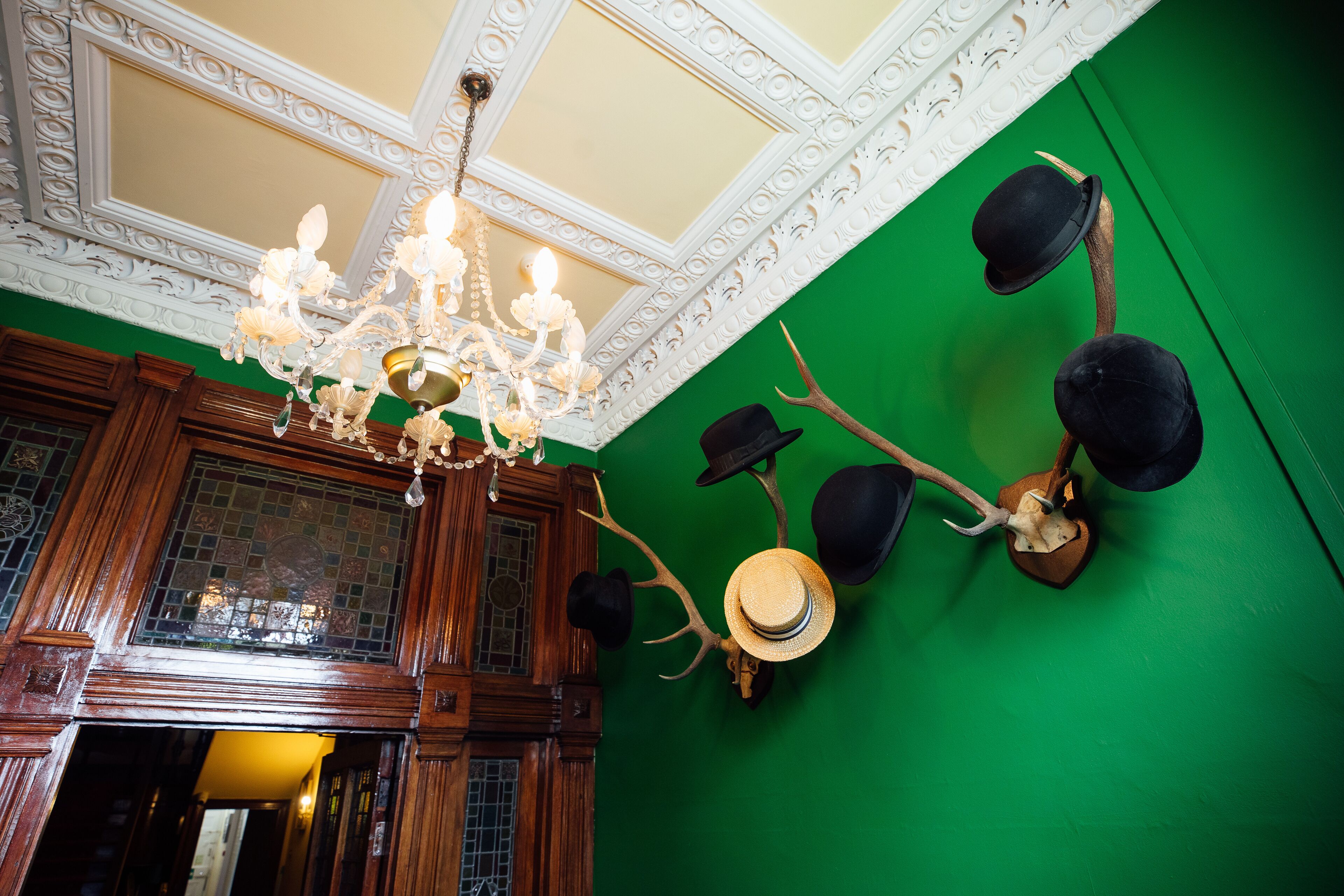 A room with a green wall, wooden paneling, and a chandelier.
