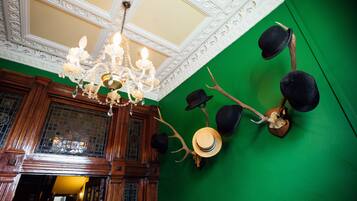 A room with a green wall, wooden paneling, and a chandelier.