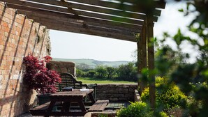 A wooden pergola with a picnic table and benches, overlooking a rural landscape with hills and greenery. - Elm Grove Country House (Tenby)