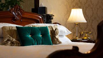 Una cama bien hecha con un almohadón verde, un cabecero de madera y una mesita de noche con una lámpara.