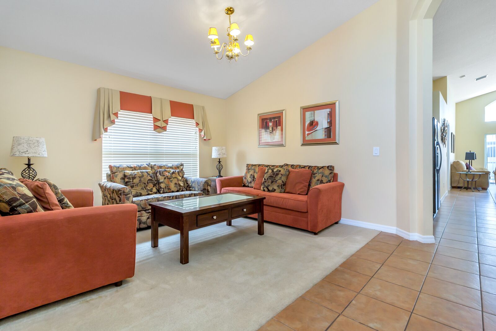A spacious living room with a sofa set, a coffee table, and a chandelier.