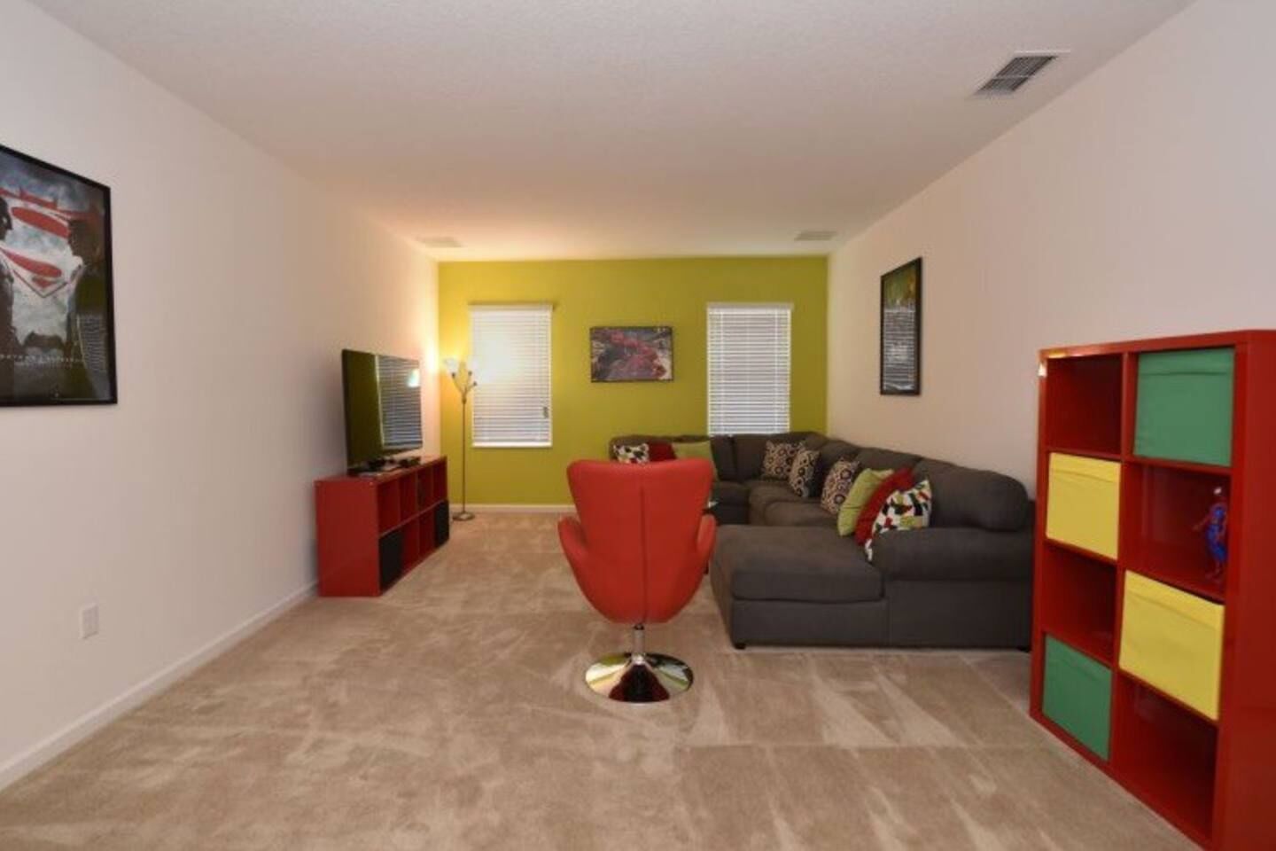 A living room with a red chair, a grey sofa, and a bookshelf.