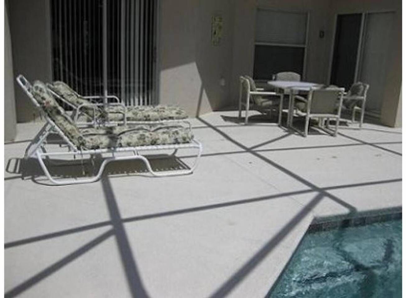 Un espace aménagé au bord de la piscine, avec des chaises longues et une table.