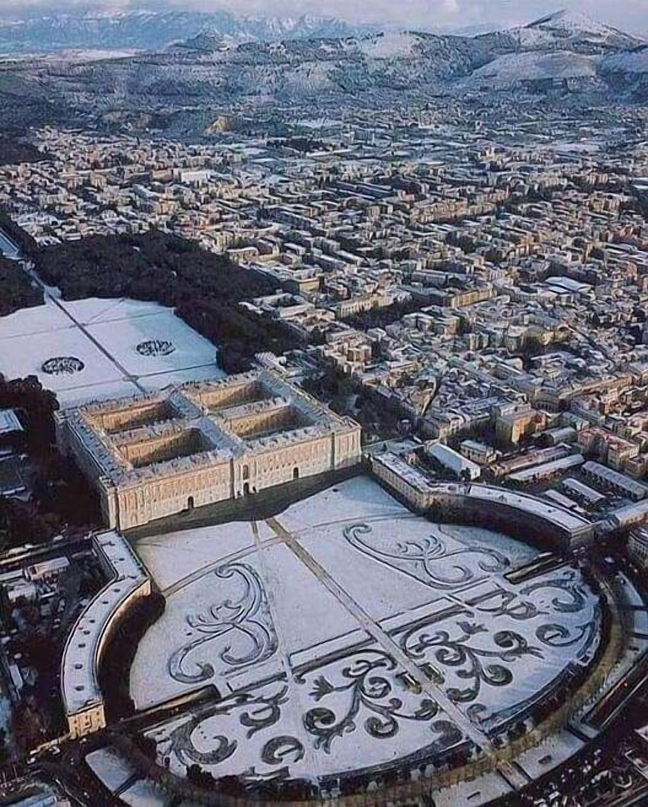 Vue aérienne d’une ville avec une grande place richement décorée et un bâtiment historique surmonté d’un dôme.