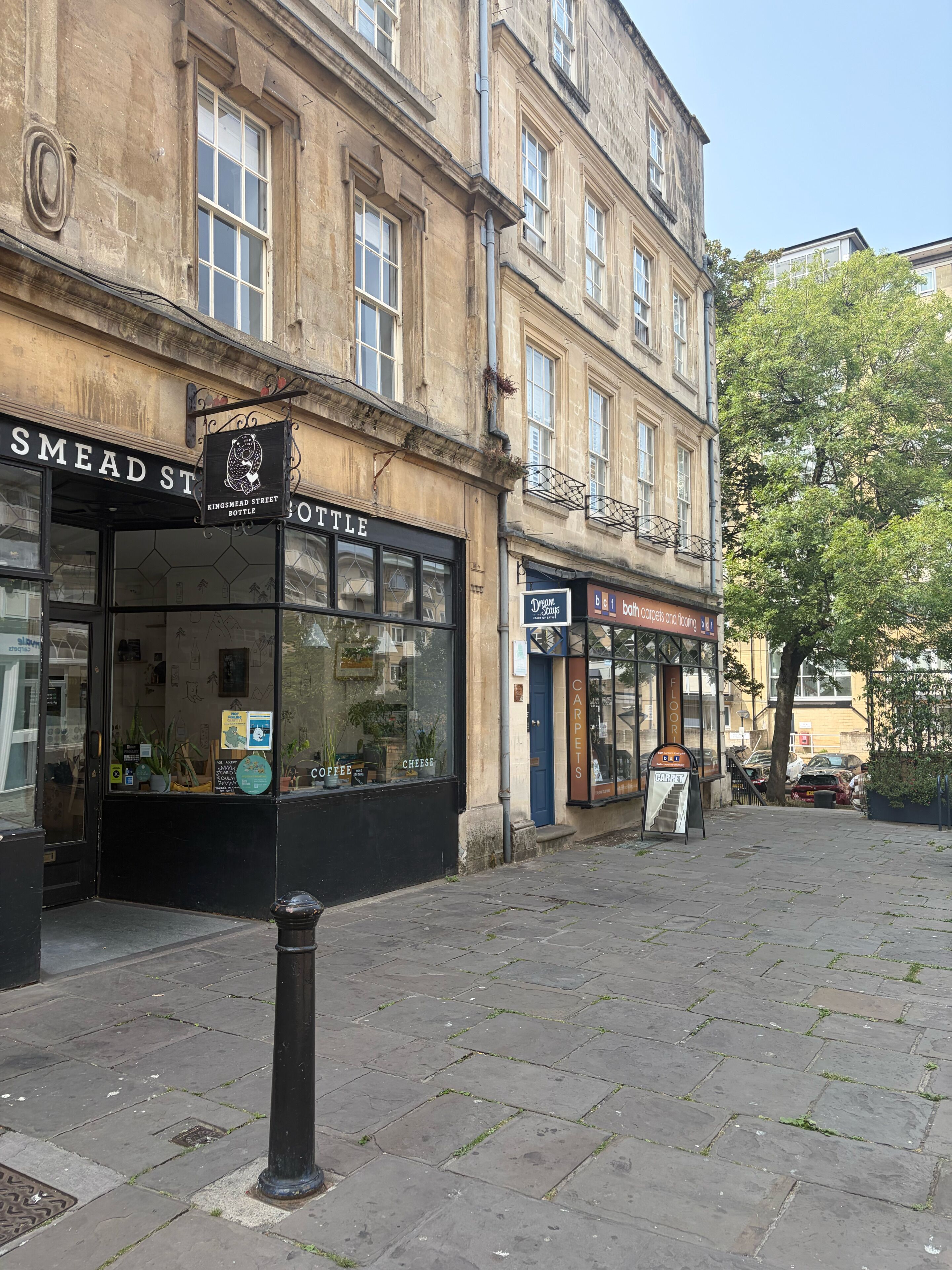 A street with shops, including a coffee shop and a carpet store.