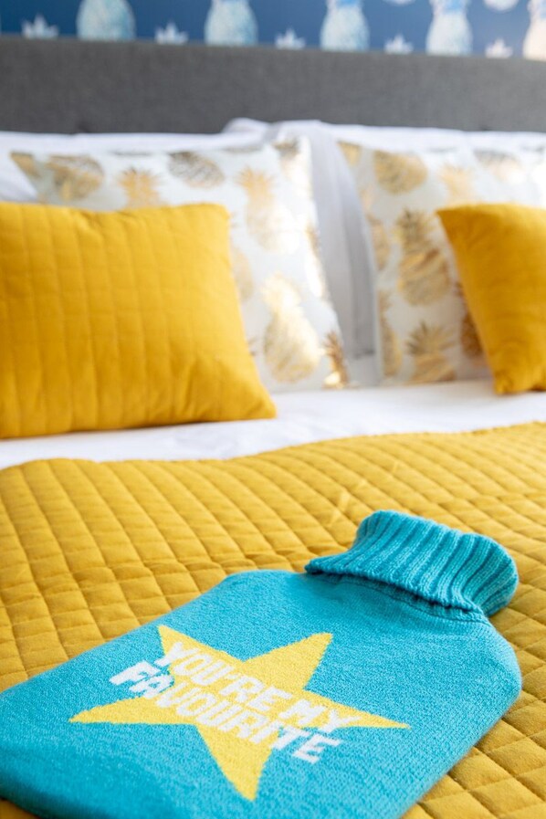 Una cama con una colcha acolchada amarilla y dos almohadas amarillas.