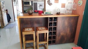 A kitchen area with a wooden countertop, two stools, a wine rack, and various kitchen appliances. - Sítio Sapiranga (Sapiranga)
