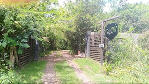A narrow dirt path leading through a lush, green area with wooden gates and a sign indicating a gate number. - Sítio Sapiranga (Sapiranga)