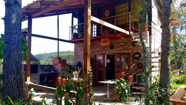 A rustic building with a brick exterior, large windows, and a wooden deck. - Sítio Sapiranga (Sapiranga)