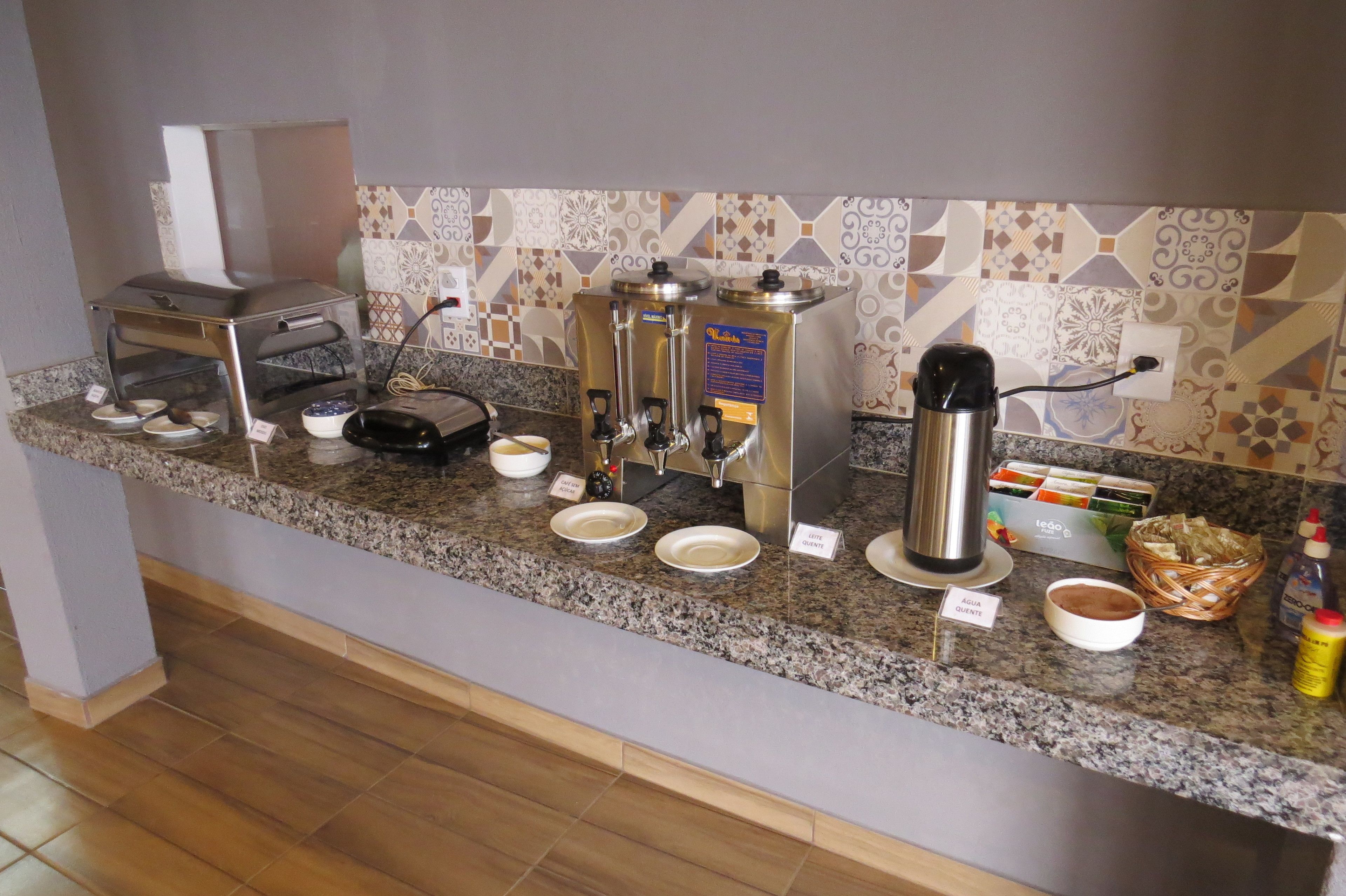 Un comptoir de petit-déjeuner équipé d’une machine à café, d’un espace pour préparer le thé et de divers aliments.