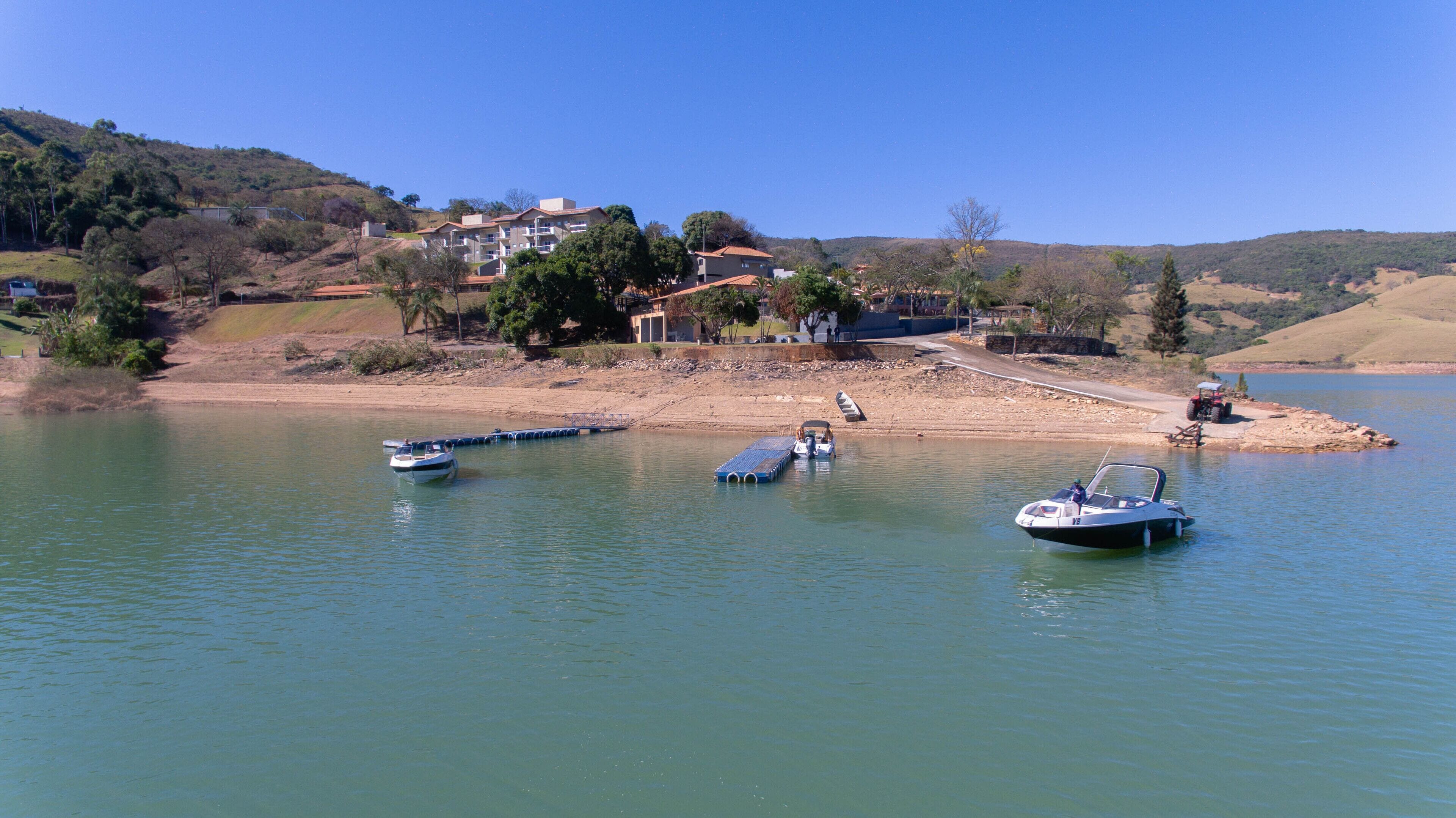 Un lago con varias embarcaciones amarradas cerca de la orilla. Se observan edificios al fondo, indicando una zona residencial.