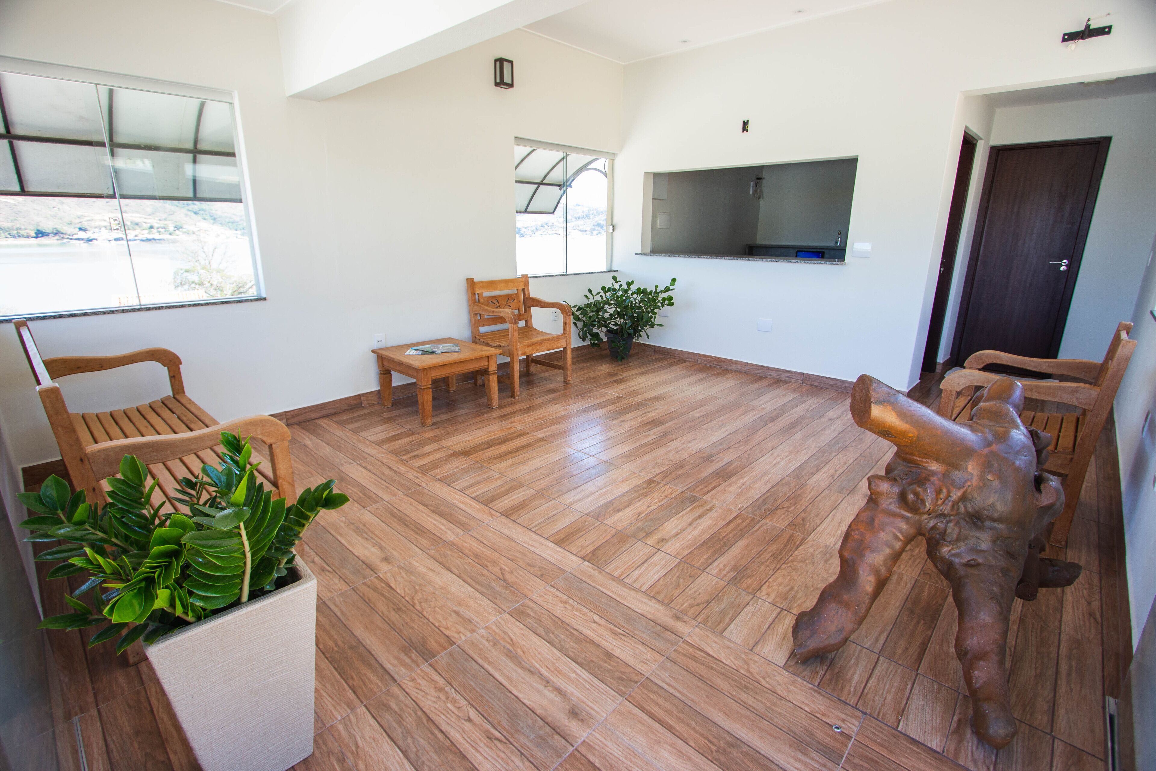 A spacious room with wooden flooring, a dining area with chairs, a potted plant, and a mounted television.