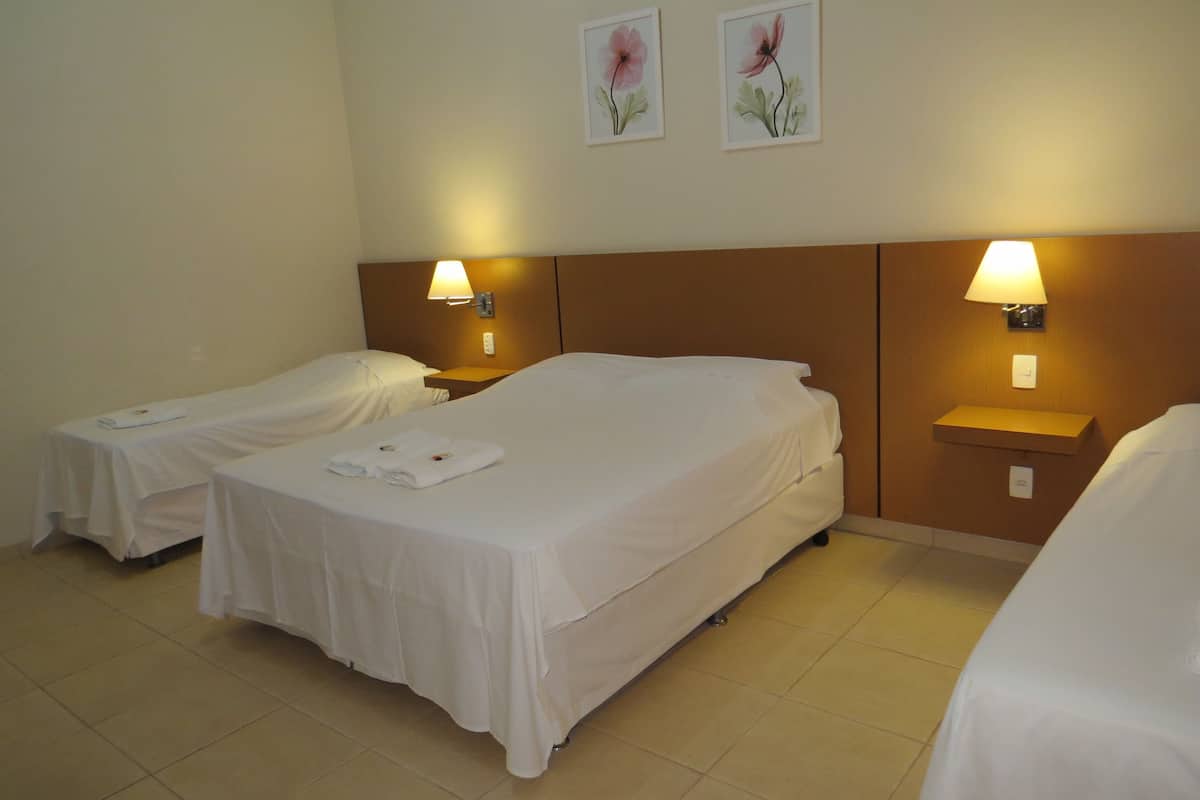 A hotel room with two single beds, each with a bedside table and lamp.