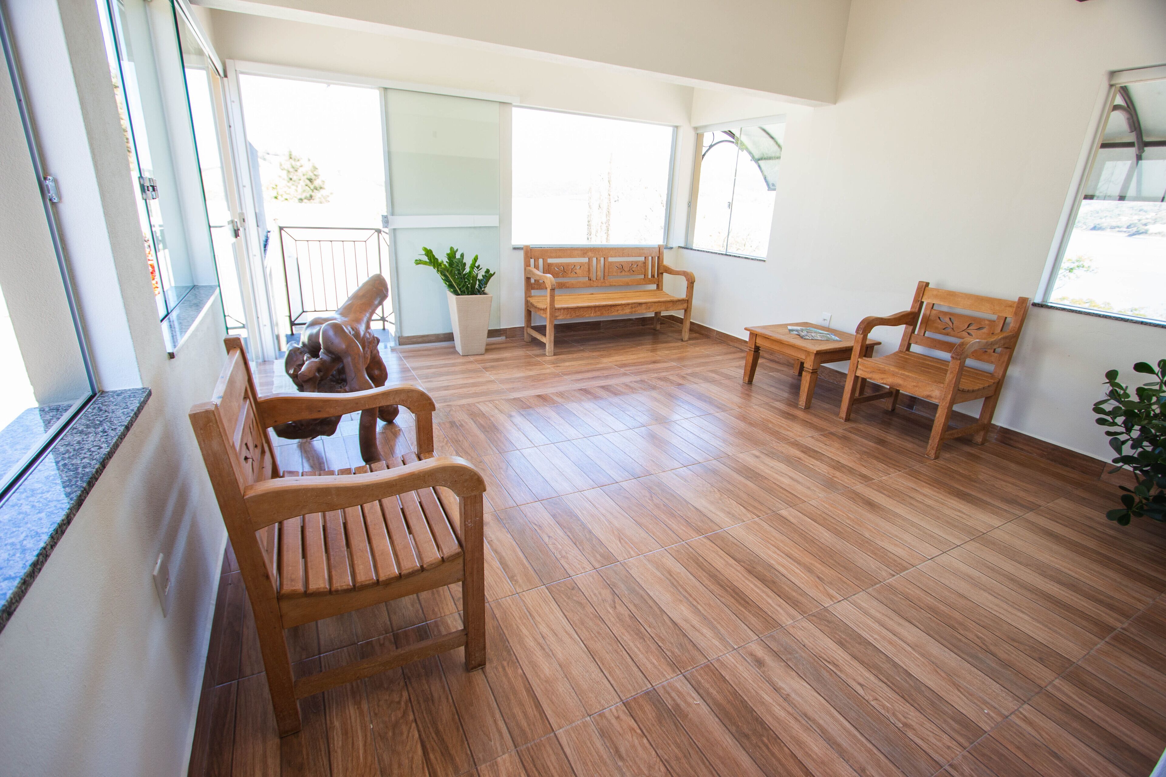 Una habitación amplia con piso de madera, un banco de madera, una silla de madera y una pequeña mesa.