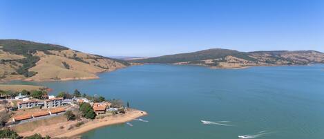 A large body of water surrounded by hills, with a small building complex on the left.