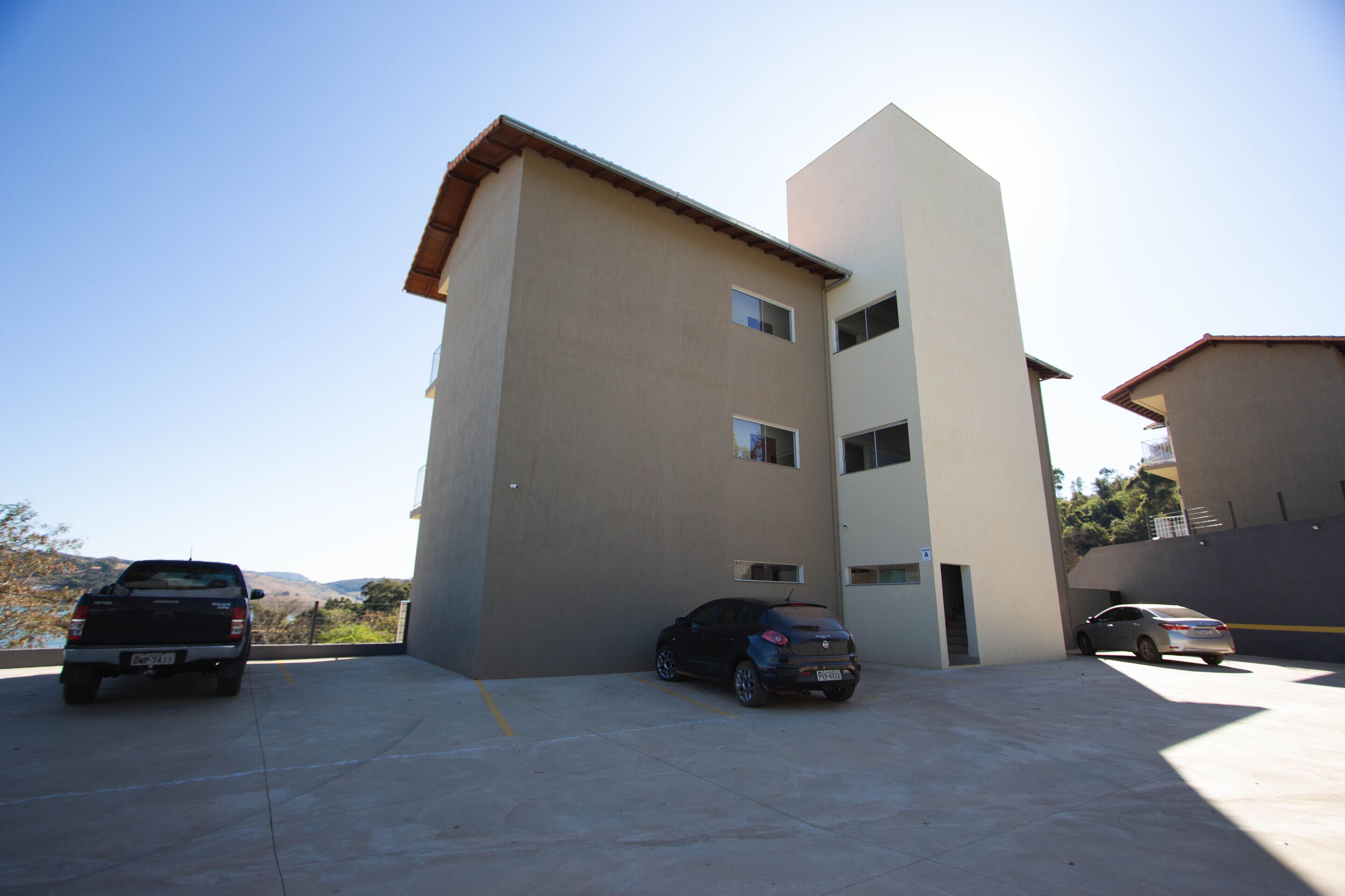 A parking area with a building that has a flat roof and a beige facade.