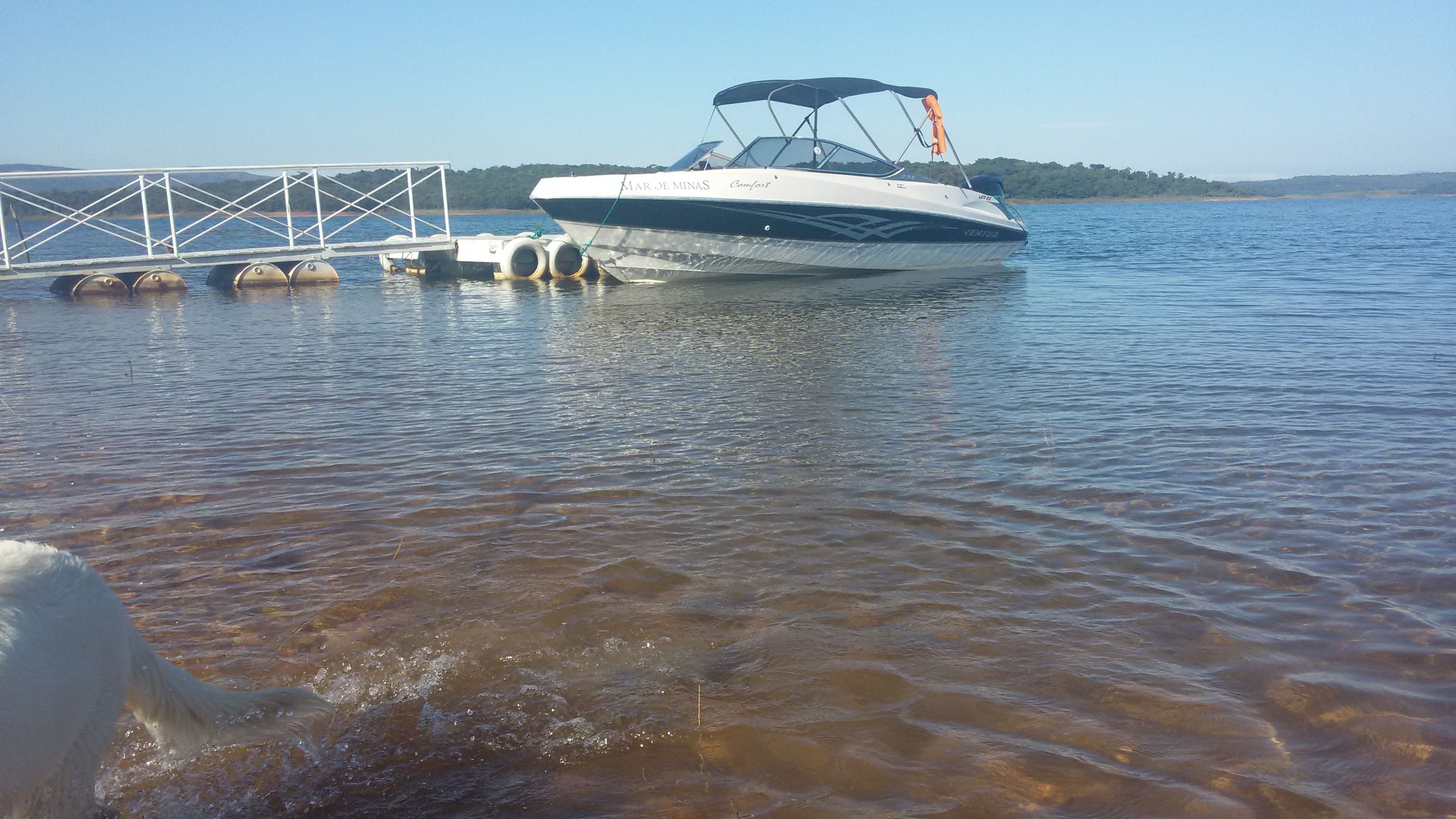 A boat docked at a pier with a clear view of the water and distant land.