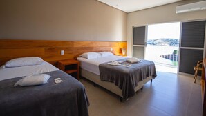 Ett hotellrum med två sängar, en sänggavel i trä, ett nattduksbord, ett fönster med utsikt och en skjutdörr.