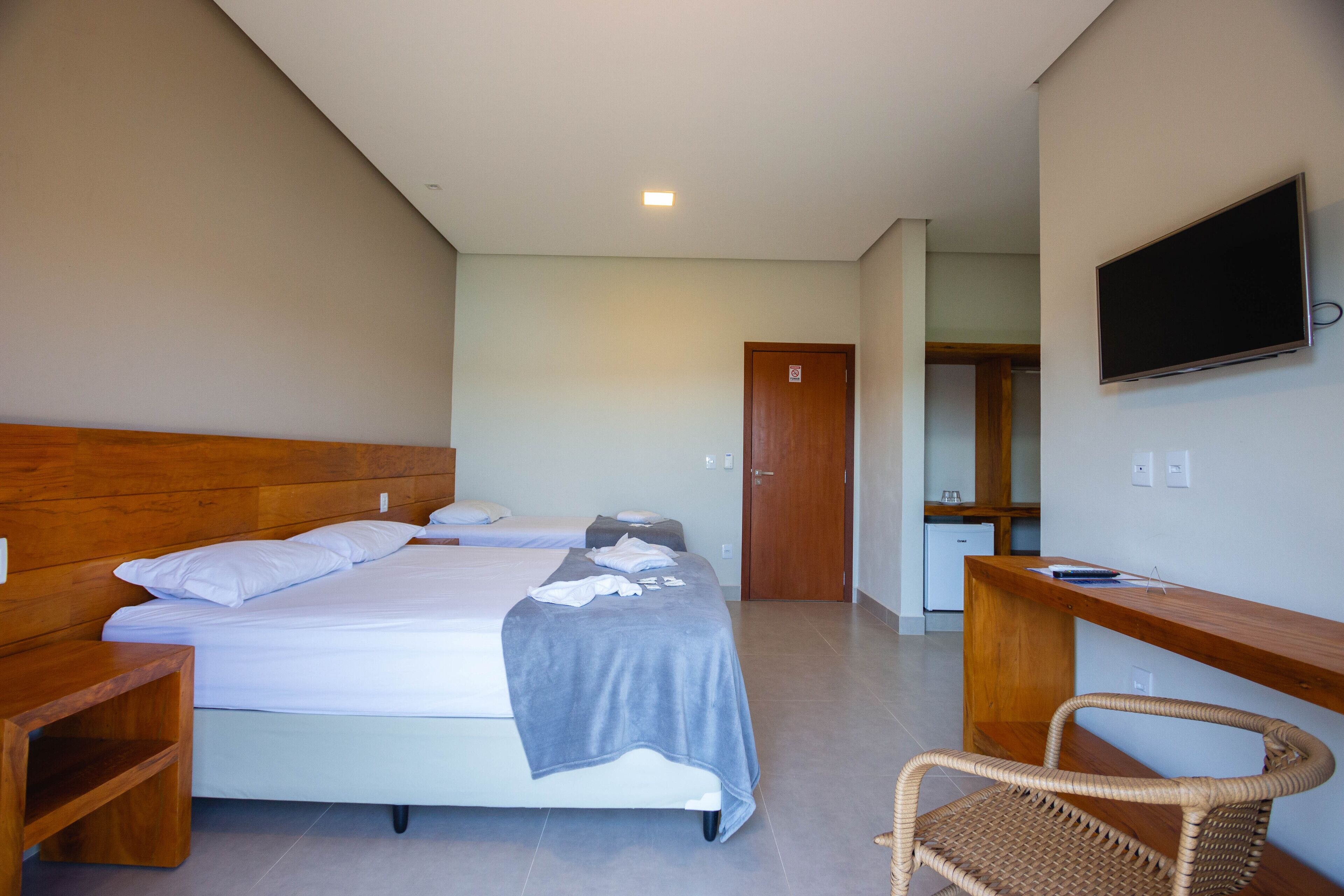 A hotel room with a bed, a desk, a chair, and a TV.