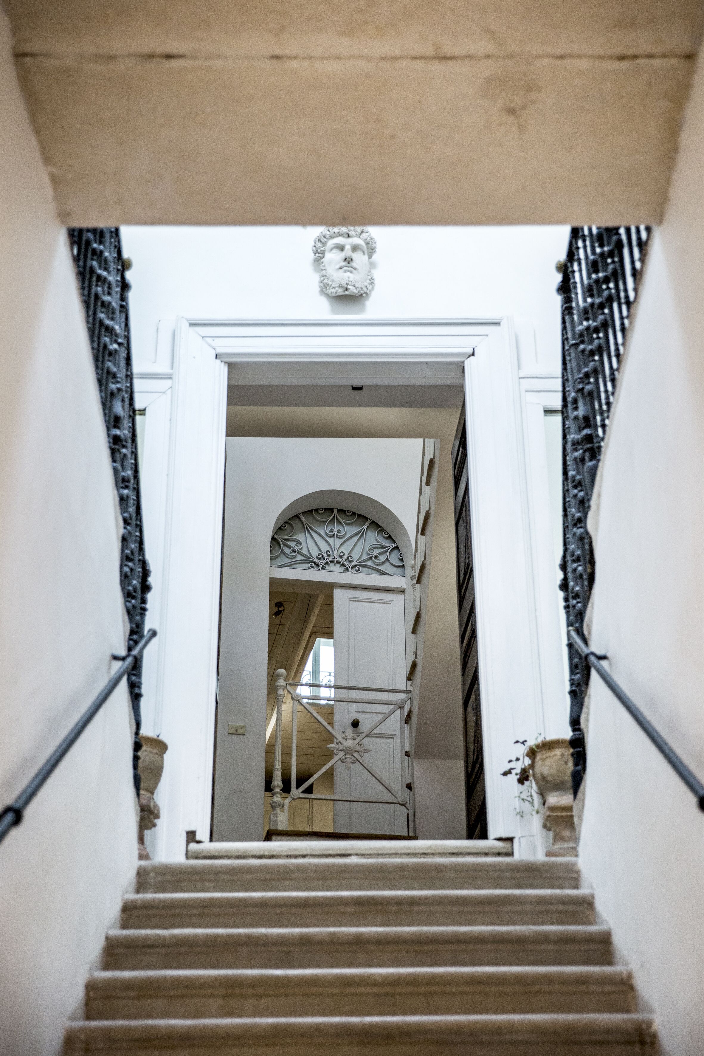 Eine Treppe führt zu einem Raum mit einer weißen Tür und einem verzierten Bogen.