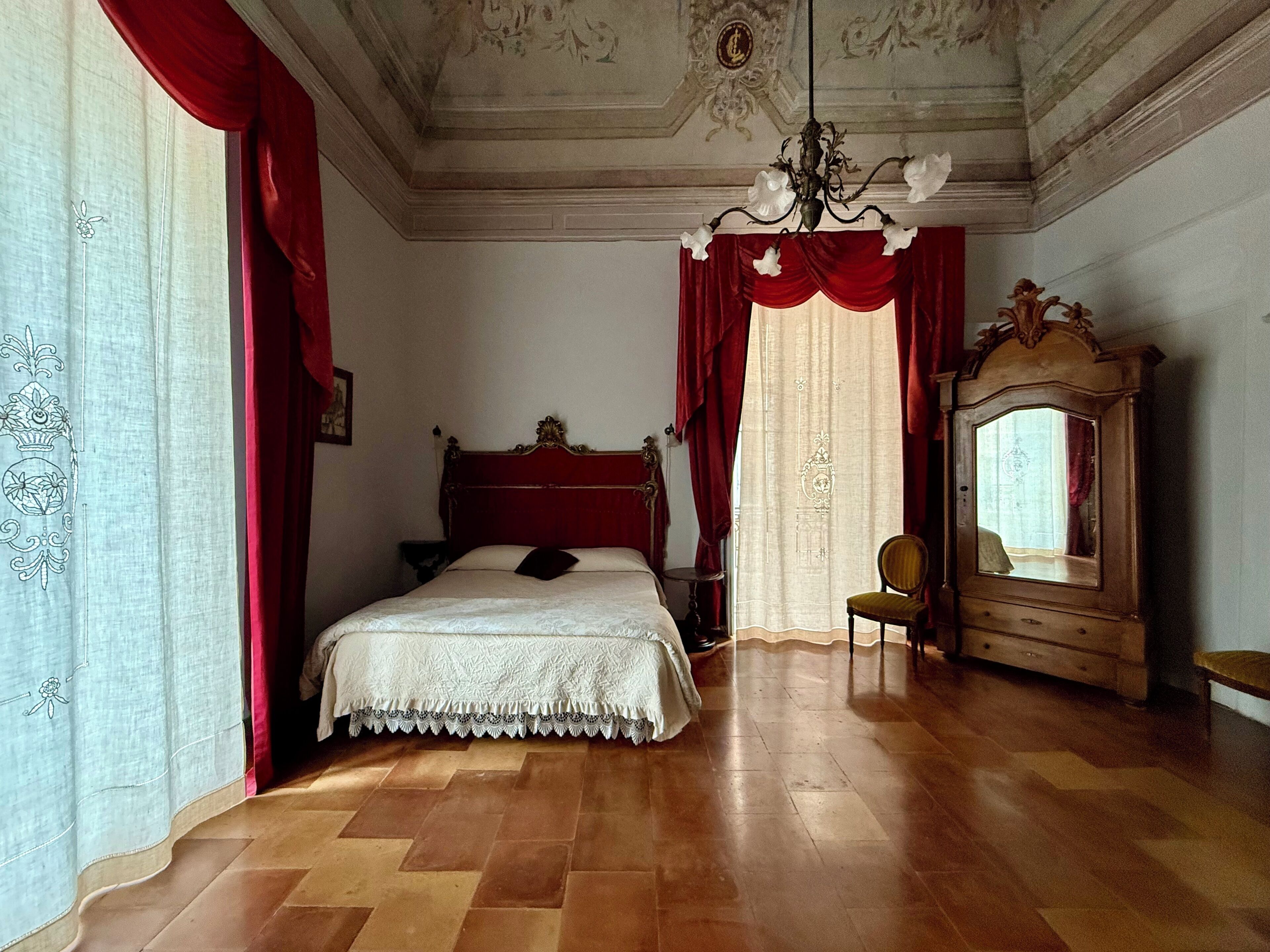 A bedroom with a wooden bed, a chair, a dresser, and a mirror.