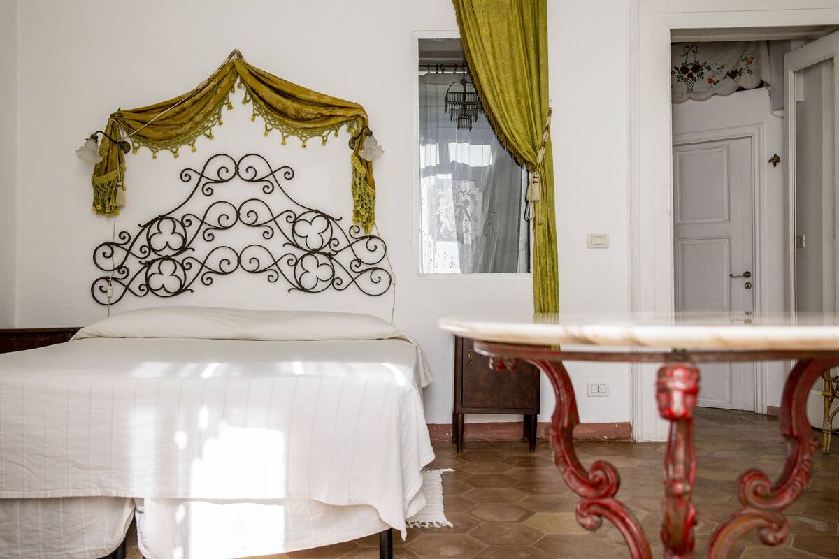Ein Schlafzimmer mit Bett, Tisch und einem verzierten Metall-Kopfteil.