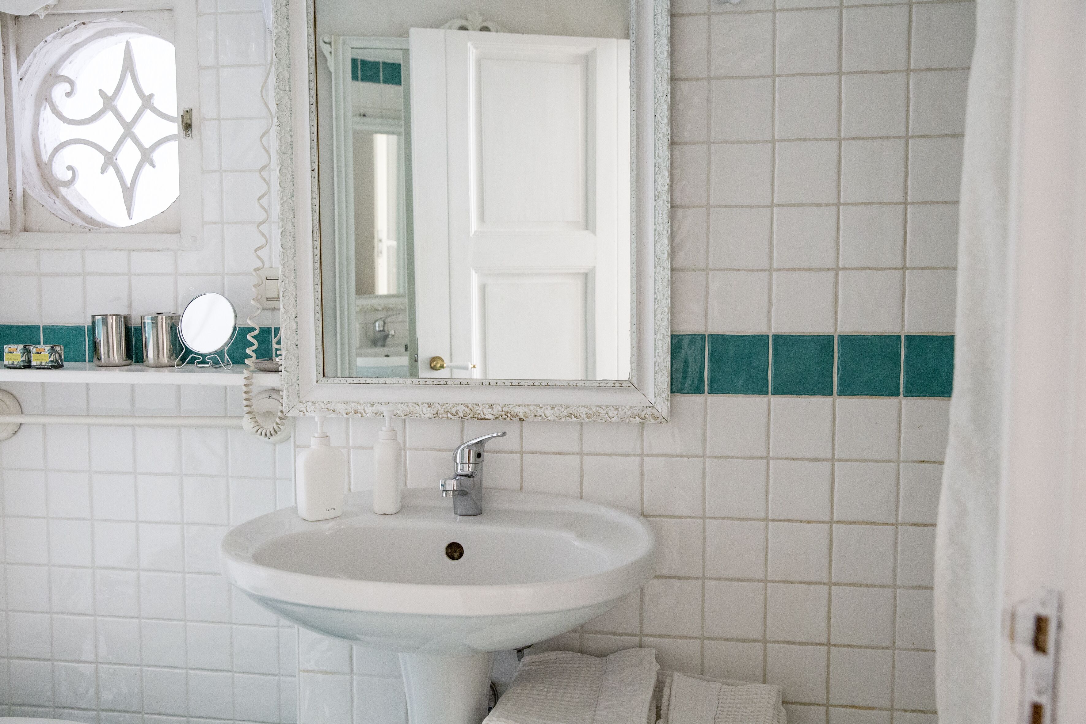 Ein Badezimmer mit einem weißen Waschbecken, einem Spiegel und einer Tür.