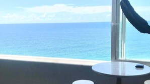 A balcony with a view of the ocean, a round table, and two bar stools. - Breathtaking Ocean View (Salvador)