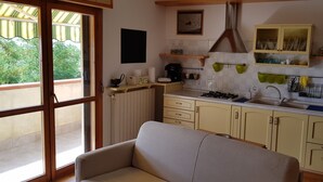 A kitchen with a sofa, a stove, a sink, and a window overlooking a balcony. - Apartment/ flat - Gavorrano (Gavorrano)