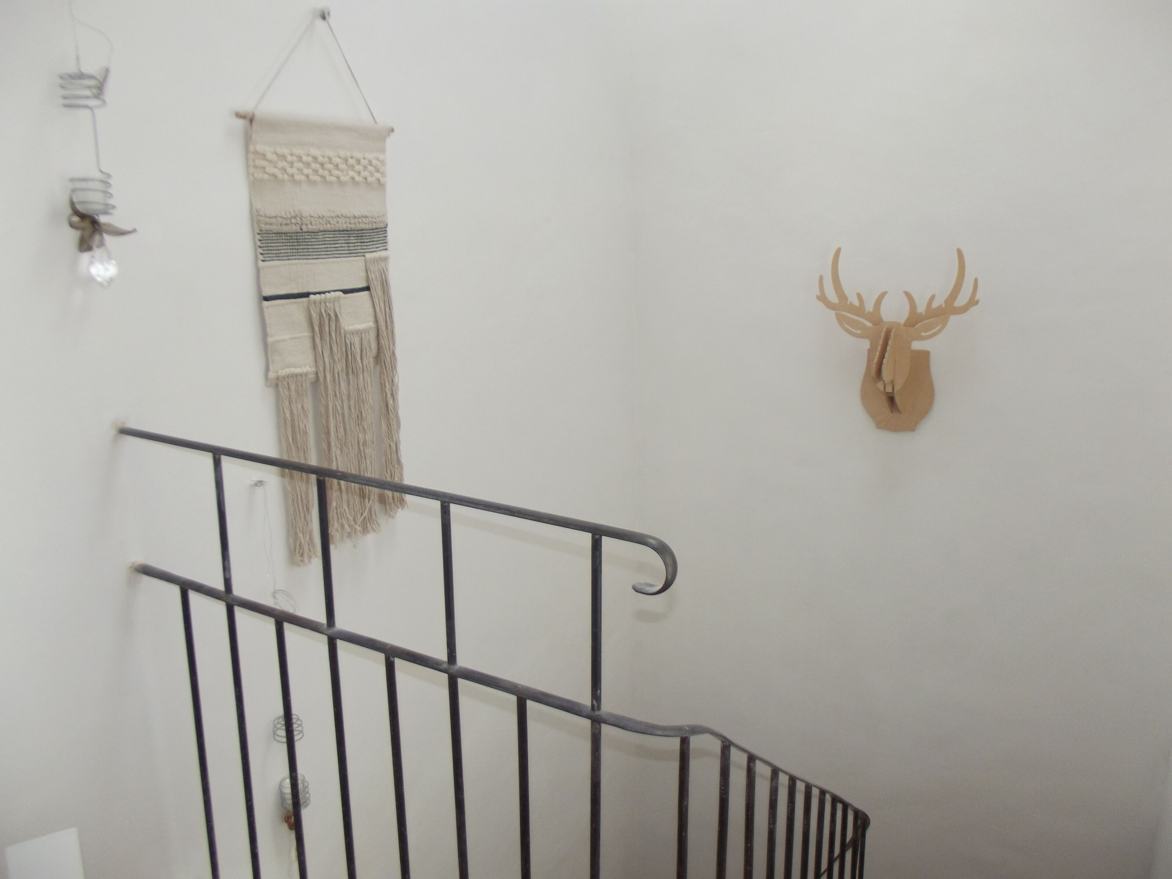 A staircase with a metal railing, a wall-mounted decorative item, and a wall-mounted animal head.