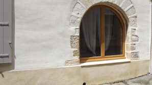 Ein Gebäude mit einem Fenster, das einen Holzrahmen und einen weißen Vorhang hat.