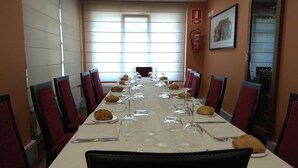 A conference room with a long table set for a meeting, equipped with chairs, plates, wine glasses, and cutlery. - Hotel Restaurante Aldama (Amurrio)