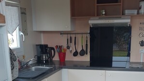 A compact kitchen with white cabinets, a black stove, and a wooden dining table with chairs.