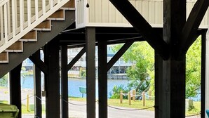 Un espace extérieur aménagé, abrité et doté d’un canapé et d’une table ronde, de poutres en bois et d’une vue sur le bord de l’eau.