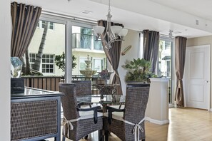 A dining area with wicker chairs, a glass table, and a chandelier. - 3bed/2ba DOWNTOWN DELRAY BEACH, WALK TO BEACH, FOOD & SHOPS! PINEAPPLE GROVE! (Delray Beach)
